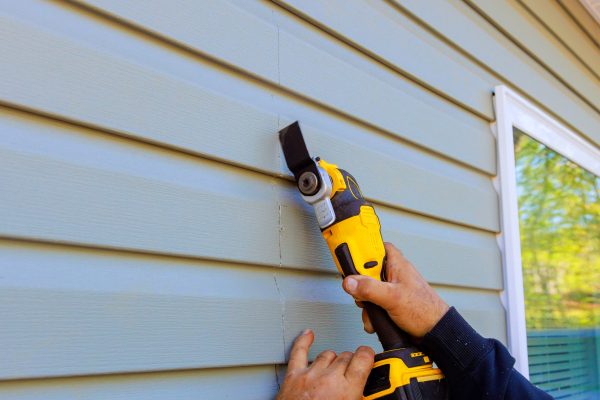 As part of reconstruction of house, multi tool is used to remove damaged vinyl siding